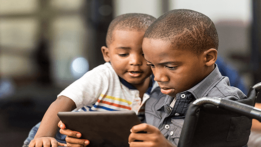 طفل أمريكي من أصل أفريقي يلعب على كمبيوتر لوحي مع أخيه الأصغر