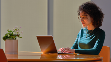 امرأة جالسة على مكتب مع كمبيوتر محمول