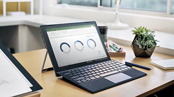 مكتب موضوع عليه جهاز كمبيوتر Surface يعرض مخططات Excel