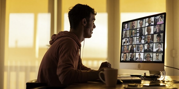 صورة لرجل على جهاز كمبيوتر مع اجتماع فيديو على الشاشة