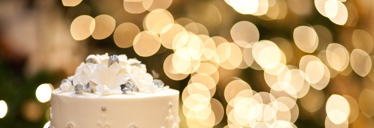 صورة كعكة زفاف مع أضواء غير واضحة في الخلفية