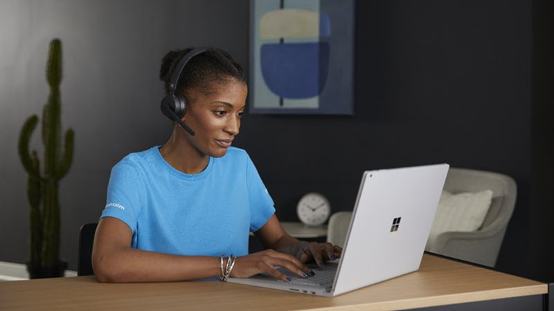 امرأة ترتدي سماعة رأس أثناء استخدام كمبيوتر محمول