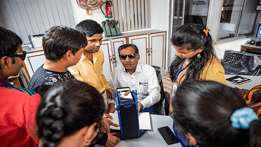 Instruktor v odborném pracovišti pro nevidomé v Indii předvádí používání technologie pro usnadnění ke čtení Braillova písma.