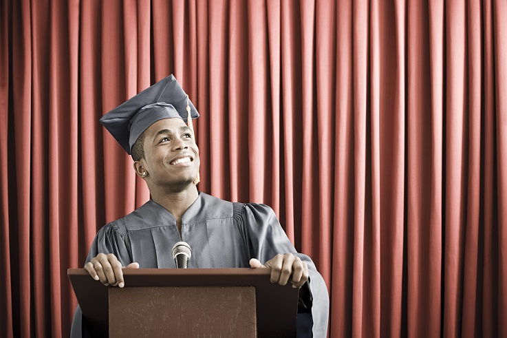 Fotka mladého muže ve slavnostním oděvu pro dokončení studia stojícího na pódiu