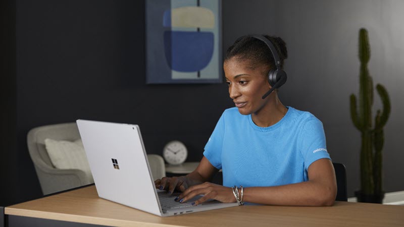 Kvinde, der har et headset på, mens hun bruger en bærbar computer