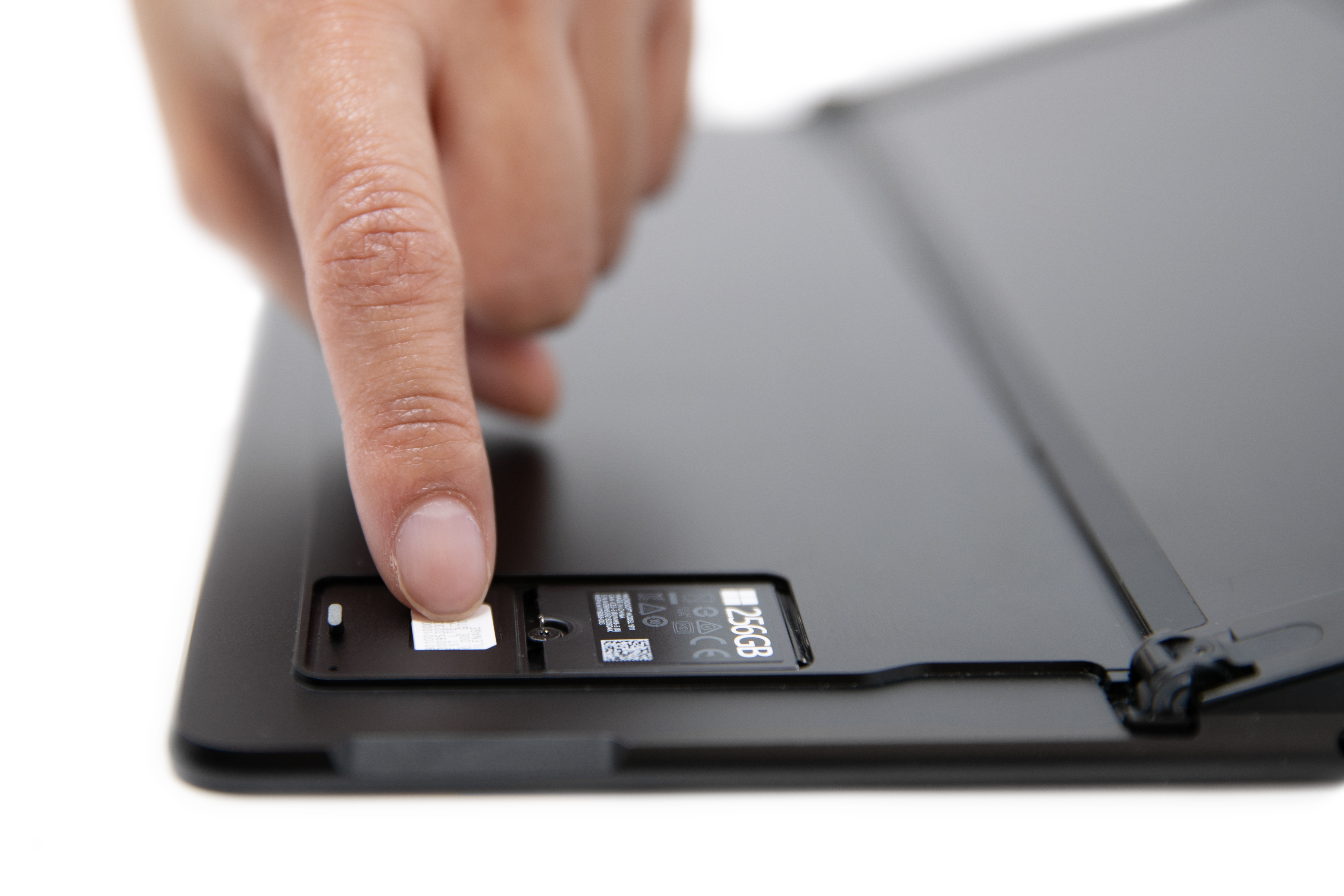 Eine Person, die eine SIM-Karte in den SIM-Einschub eines Surface Pro X schiebt.