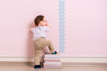 Ein kleines Kind steht neben einem Wachstumsdiagramm