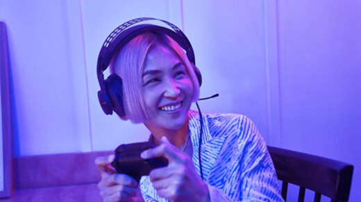 Μια γυναίκα που φοράει ακουστικά παιχνιδιών ενώ κρατάει ένα χειριστήριο Xbox.