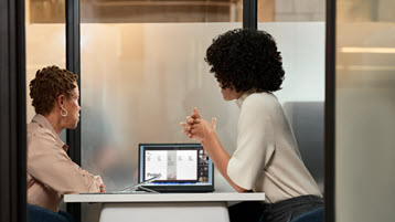 Two women sitting in front of a laptop