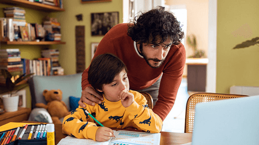 Un padre y un niño haciendo tareas escolares en casa.