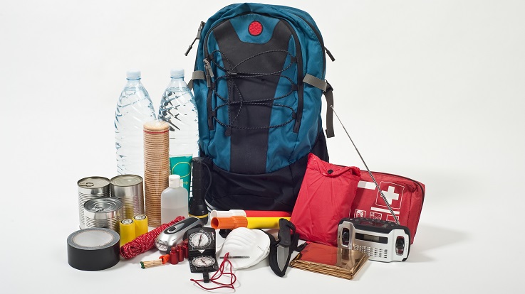 Foto de una mochila, un kit de primeros auxilio, una radio, agua y otros suministros de emergencia.