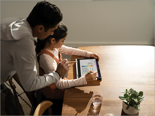 Un padre ayuda a su hija a trabajar en una tableta en Bloc de notas de clase