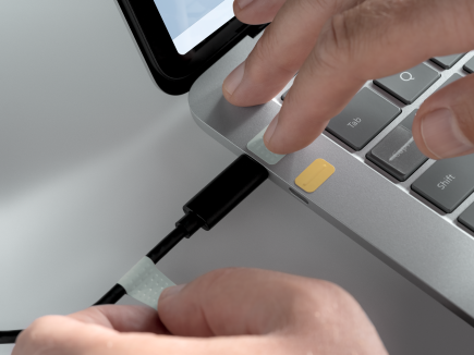 Mies, joka yhdistää USB-C-kaapelin USB-C-porttiin porttitarrojen avulla.