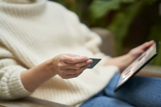 Une femme tient une carte de crédit et un téléphone portable