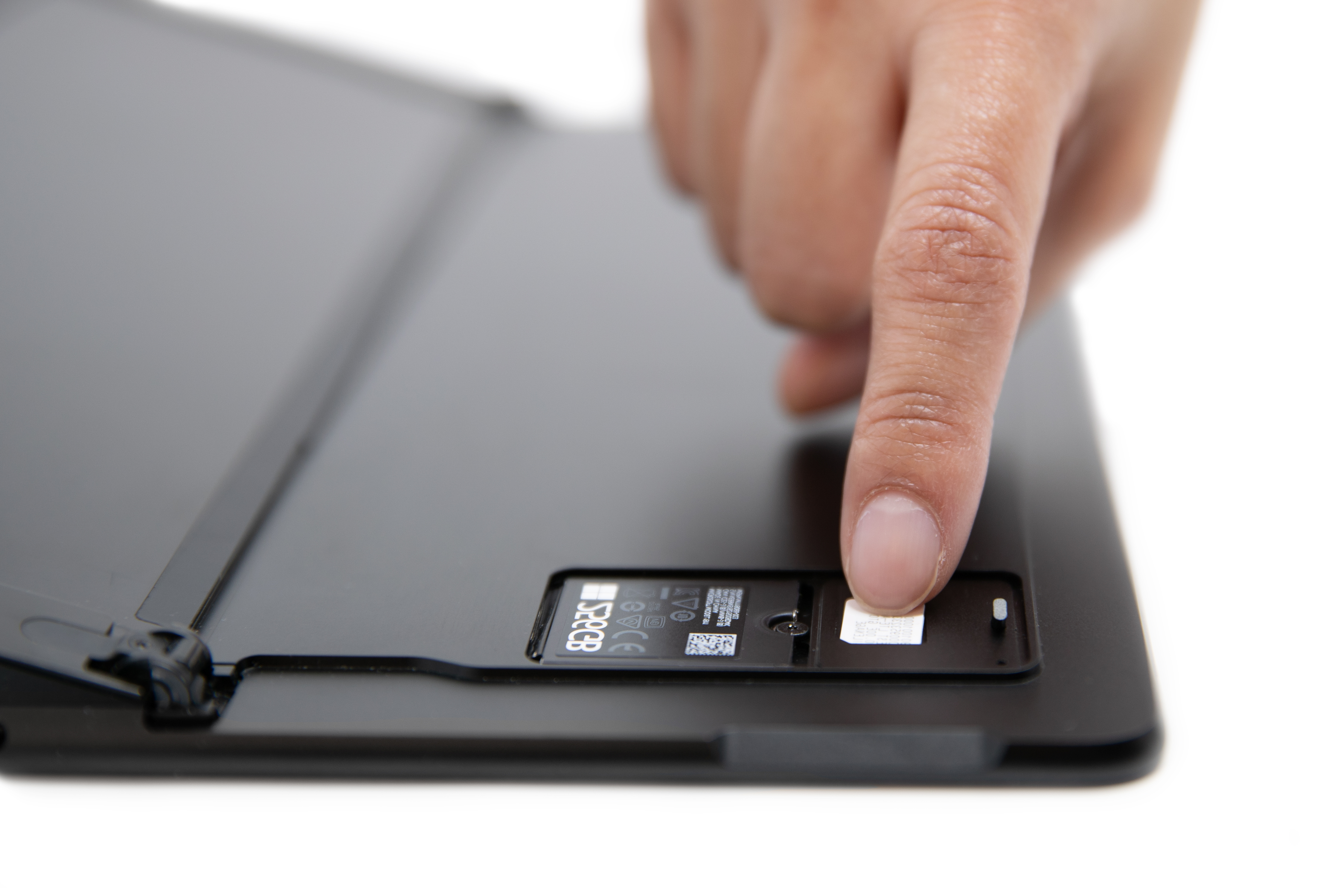 אדם גולש בכרטיס SIM לתוך החריץ של Surface Pro X SIM.