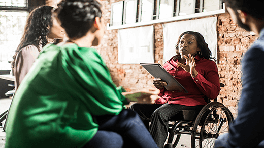 אשת עסקים בכיסא גלגלים מובילה דיון קבוצתי במשרד יצירתי