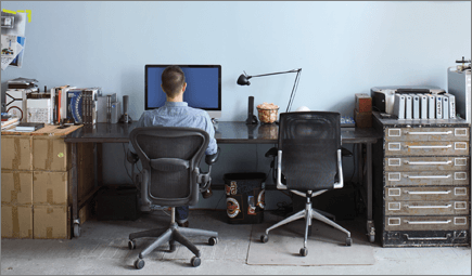 צילום של אדם היושב ליד שולחן עבודה, עובד במחשב.