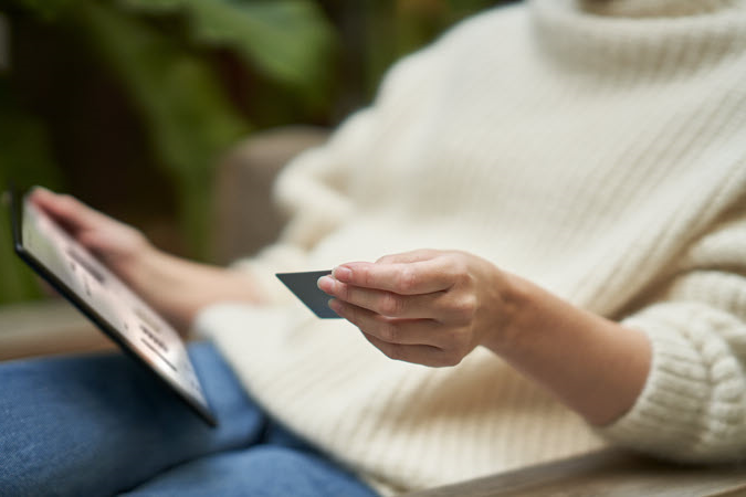 אישה מחזיקה כרטיס אשראי ומחשב נישא