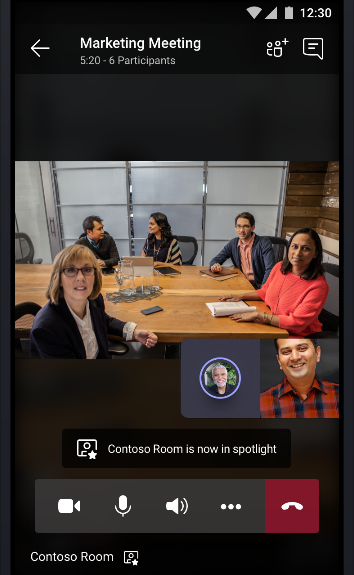 Slika mrežnog sastanka tima na kojoj puna soba za sastanka priča s još dva sudionika na sastanku.