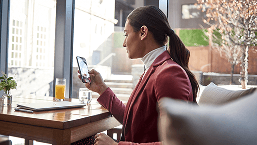 Női vezető egy asztalnál ülve mobileszközt használ