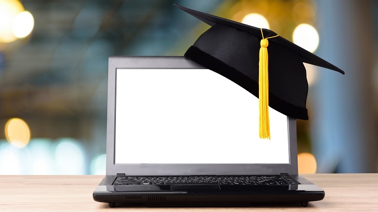 Photo of a graduation cap and laptop
