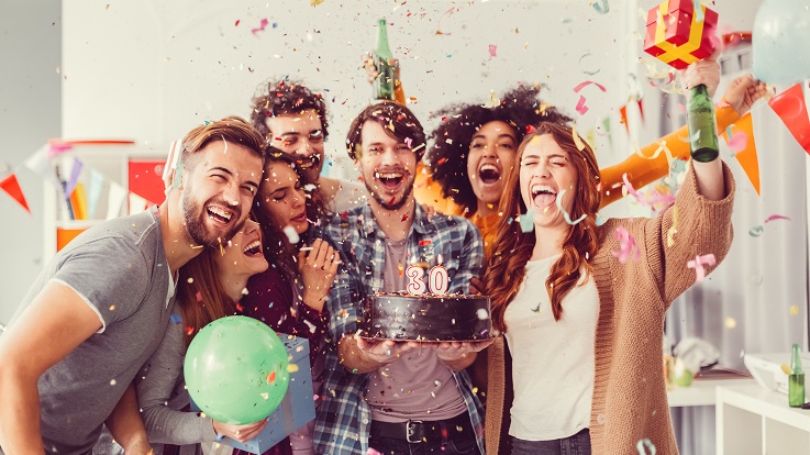 食べ物や飲み物に囲まれて、紙吹雪でお祝いをする友人グループの写真。