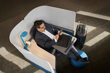 En person som sitter i en stol med en bærbar datamaskin.