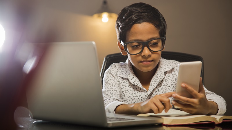 Foto van een jonge student die een quiz op een laptop neemt.