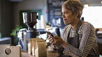 Een barista controleert haar telefoon in een café