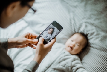 Uma mãe a tirar uma foto de telemóvel do seu bebé