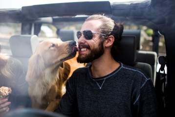 Câine lingând fața unui bărbat