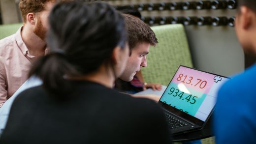 Un grup de persoane uitându-se la un ecran de computer mărit