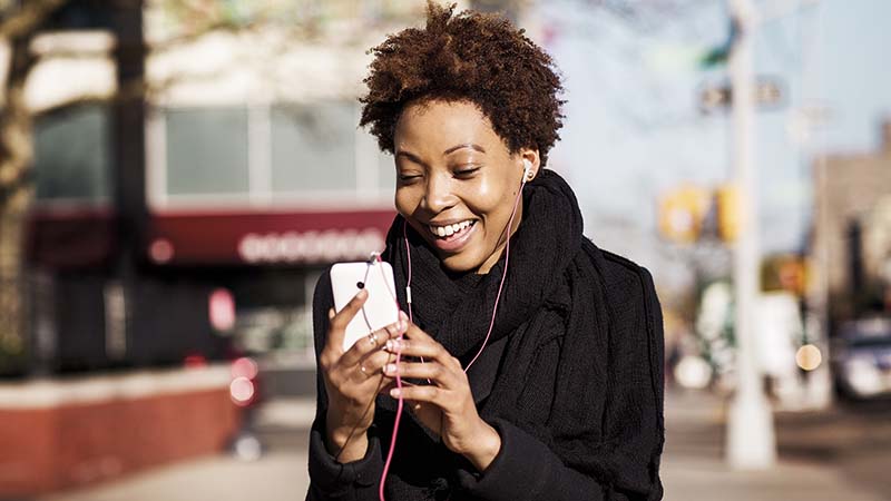 En kvinna med earbuds och en smartphone