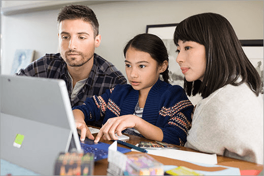 两名成人和一名儿童看着笔记本电脑